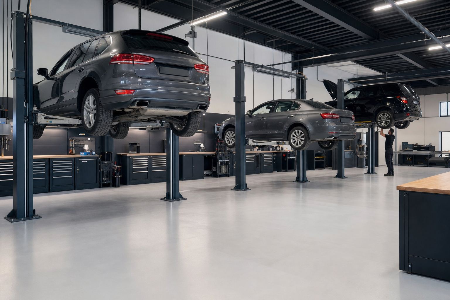 Blick in die Werkstatthalle: drei Hebebühnen mit Fahrzeugen, aufgeräumte Arbeitsplätze